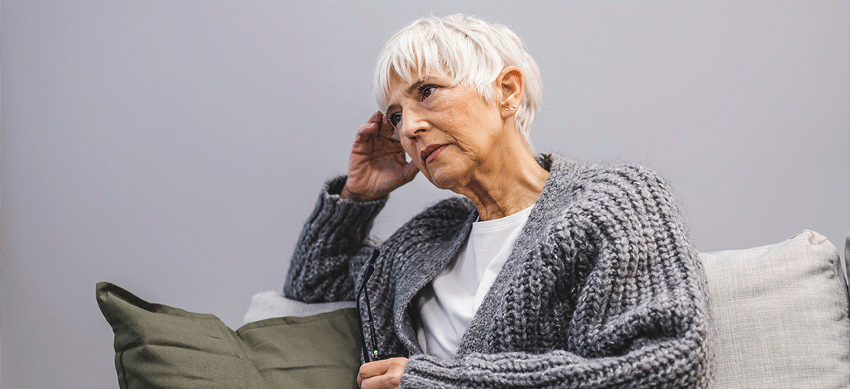 Mature woman with dementia sitting on a couch.