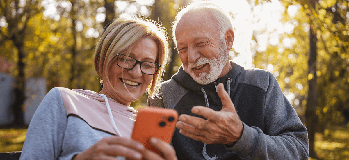 mature couple with hearing loss talking outside on park bench